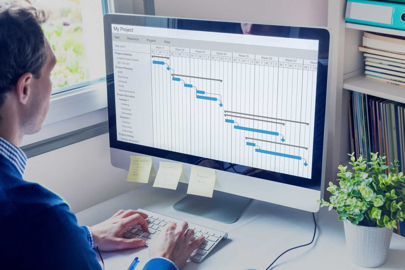 Project manager working on Gantt chart schedule to create planning with tasks and milestones to plan activities, person working with management tools on computer in office